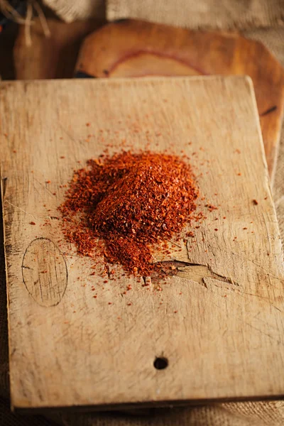 Red hot chillies pepper flakes on wooden board background — Stock Photo, Image