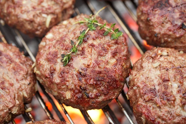 Raw burgers on bbq barbecue grill with fire — Stock Photo, Image