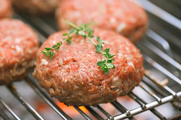 Raw burgers on bbq barbecue grill with fire — Stock Photo, Image