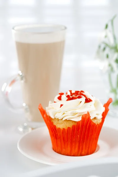 Rode feestelijke muffin en koffie latte in een glas, op witte houten t — Stockfoto