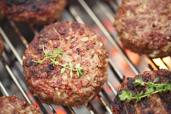 Carne de comida - hamburguesas de carne de res en barbacoa parrilla con llama —  Fotos de Stock