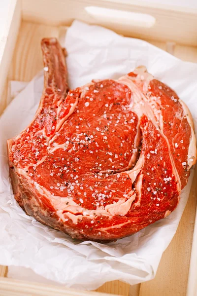 Bone-in Rib eye Steak steak on paper and wooden table — Stock Photo, Image