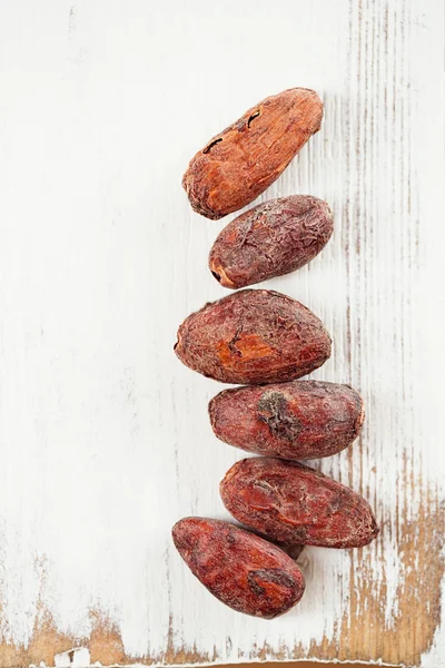 Fèves de chocolat au cacao rôti sur fond de bois blanc — Photo