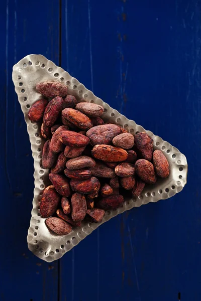 Roasted cocoa chocolate beans on dark blue wood background — Stock Photo, Image