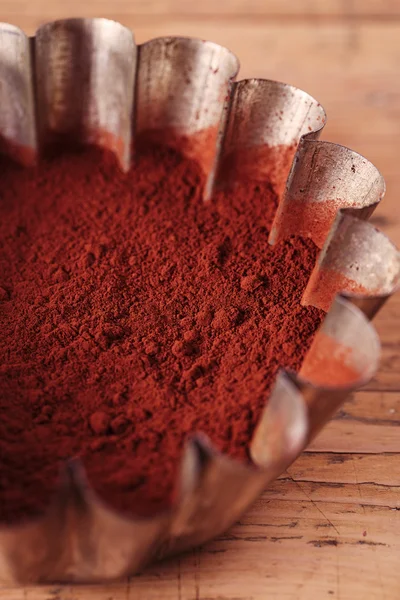 Granos de cacao en tamiz con cacao en polvo en estañería sobre respaldo de madera — Foto de Stock