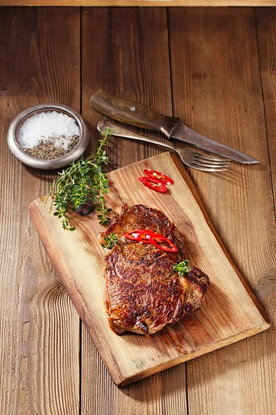 Biefstuk met rode pepers op hout en tabel — Stockfoto