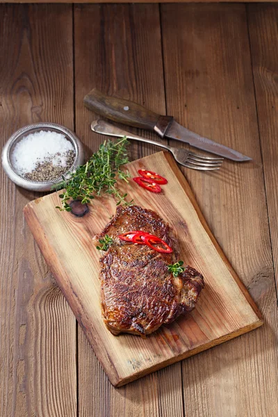 Biefstuk met rode pepers op hout en tabel — Stockfoto