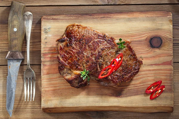 Filete de ternera con chiles rojos en madera y mesa — Foto de Stock