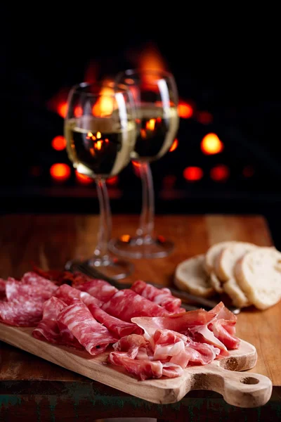 Tallrik av serrano jamon botade kött med mysig öppen spis och vin — Stockfoto