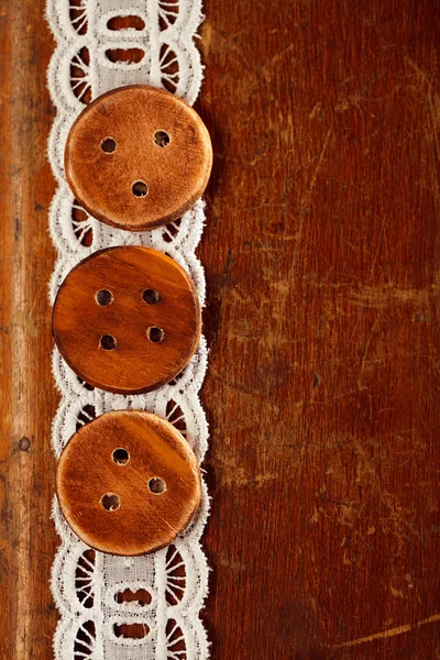 Three handmade wooden bottons on old table and lace — Stock Photo, Image