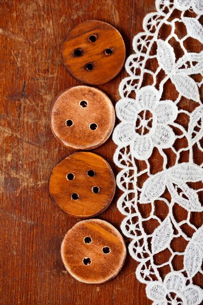 Three handmade wooden bottons on old table and lace — Stock Photo, Image