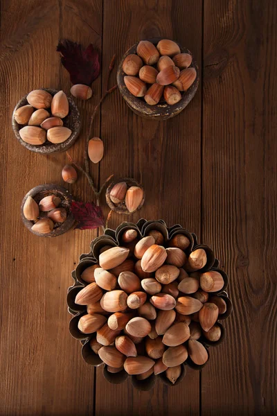 Wild hazelnut in iron bowls on wooden table — Stock Photo, Image