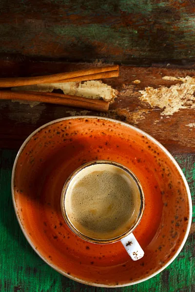 Ένα φλιτζάνι καφέ με κανέλα μπαστούνια στο ξύλο — Φωτογραφία Αρχείου