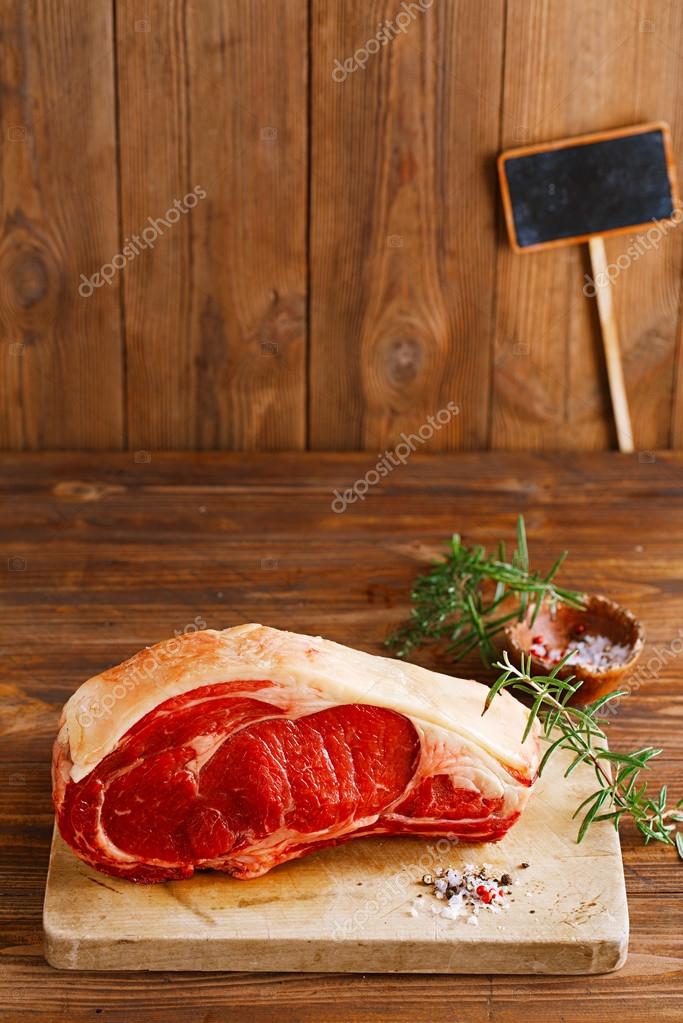 Raw beef Rib bone steak on wooden board and table — Stock Photo © lvenks 36851117