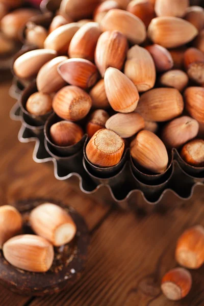 Dziki orzechów laskowych w żelaza miski na drewnianym stole — Zdjęcie stockowe