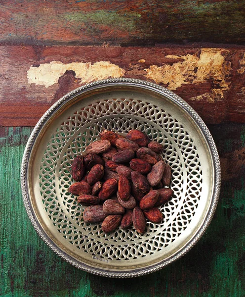 Cacao tostado frijoles de chocolate en plato de plata sobre fondo de madera — Foto de Stock