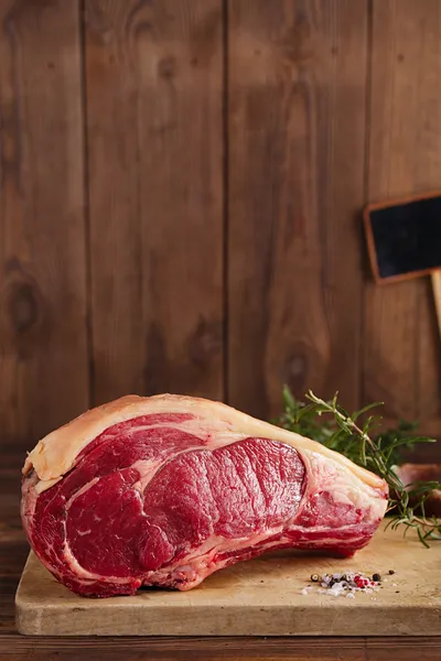 Ruwe rundvlees rib bone steak op houten plank en tabel — Stockfoto