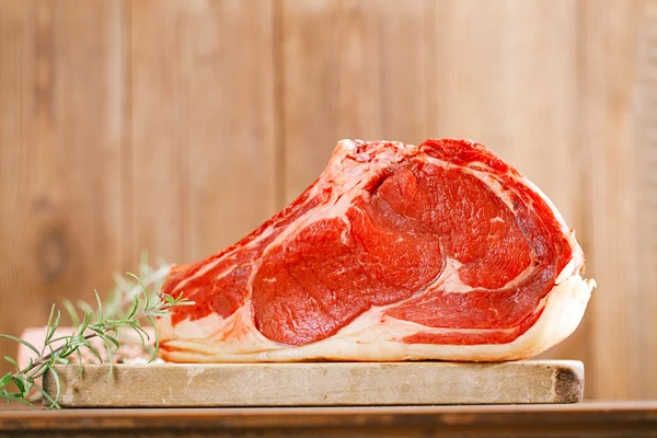 Carne cruda Filete de costilla con hueso sobre tabla y mesa de madera — Foto de Stock