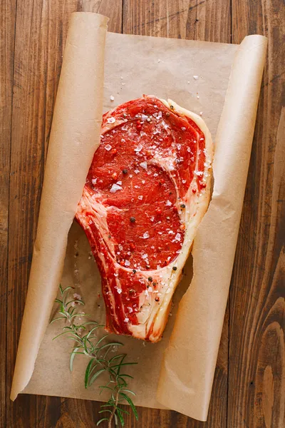 Syrové hovězí žebra steak s kostí na dřevěném prkénku a tabulka — Stock fotografie