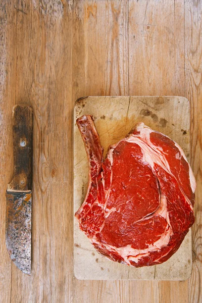 Bone-in Rib eye Steak steak on paper and wooden table — Stock Photo, Image