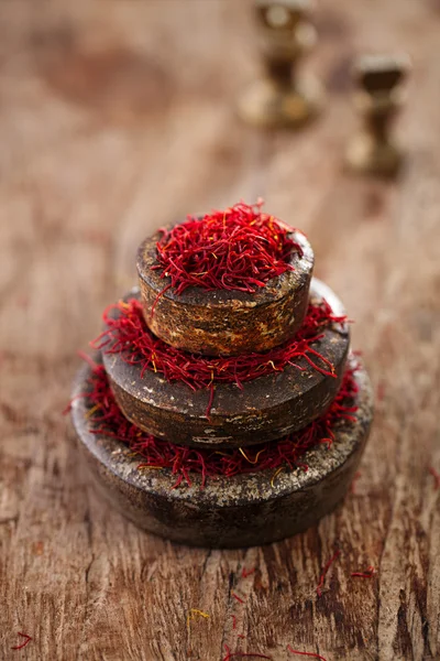 Saffron spice in antique vintage iron bowls weights stacked on w — Stock Photo, Image