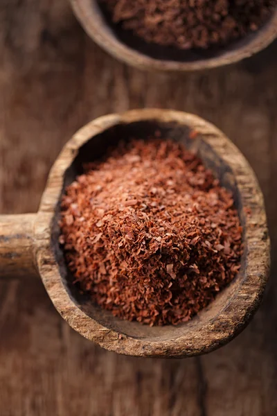 Fine grated chocolate in old wooden spoon — Stock Photo, Image