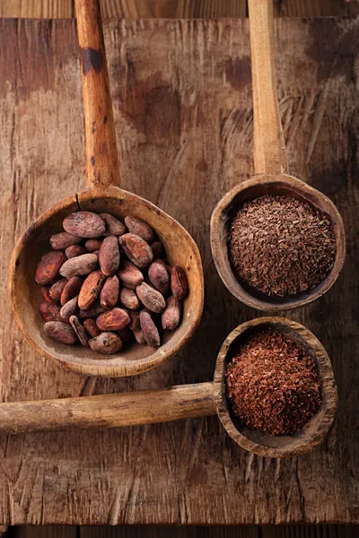 Granos de cacao, hojuelas de chocolate caliente y chocolate negro rallado en o —  Fotos de Stock