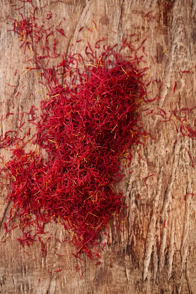 Saffron spice in pile on old wooden background, closeup — Stock Photo, Image