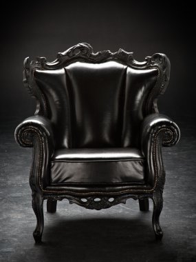old black chair, upholstered in leather, isolated on a black bac clipart