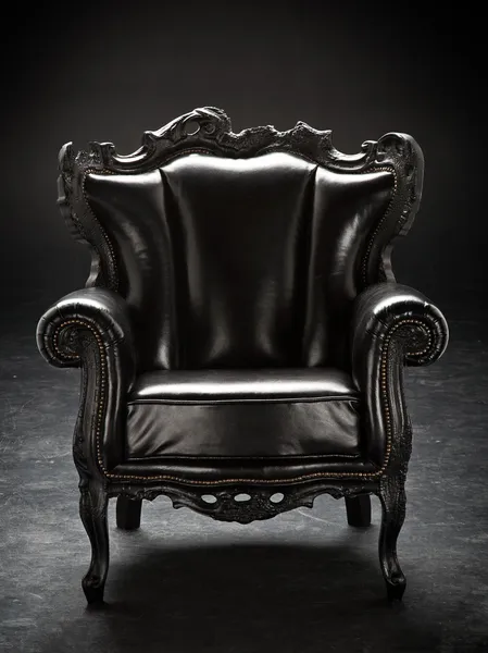Oude zwarte stoel, bekleed met leer, geïsoleerd op een zwarte bac Stockafbeelding