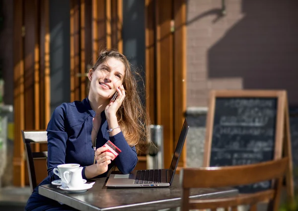 Mujer de negocios con tarjeta de crédito y portátil sentado en una mesa en —  Fotos de Stock