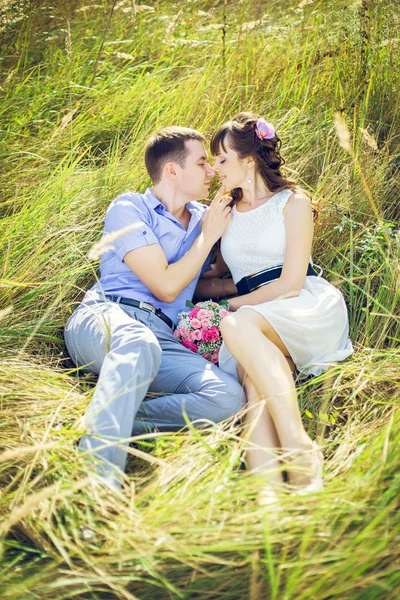 Girl with a guy lying in the tall grass — Stock Photo, Image