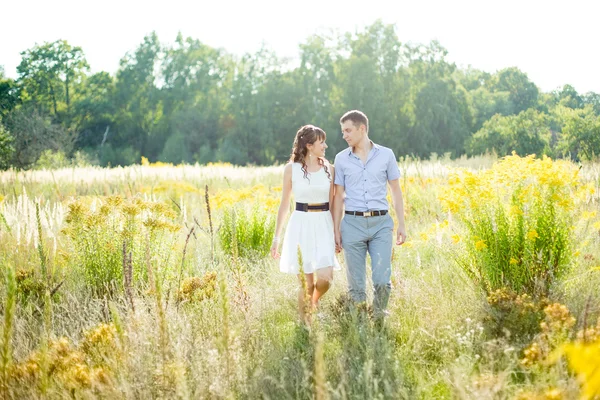 Ritratto di un ragazzo e una ragazza che camminano in un campo di alta g gialla — Foto Stock