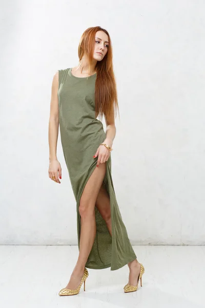 Fille maigre avec de longues jambes en robe verte posant contre un blanc — Photo