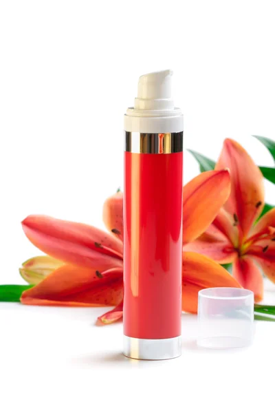 Face/body care concept: bottle of cream/lotion with lily flowers — Stock Photo, Image
