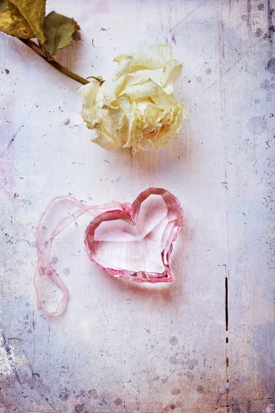 Coeur en verre rose avec rose séchée, photo stylisée âgée — Photo