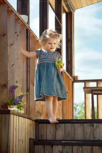 Young girl standing on a country house wooden stairs and holding — Stock Photo, Image