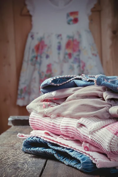 Still life with various girls clothes on an old wooden chest of — Stock Photo, Image