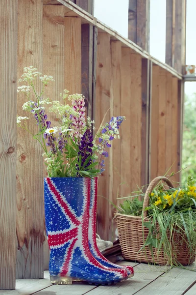 Fiori selvatici in Union Jack stivali di gomma-wellies su un paese hou — Foto Stock