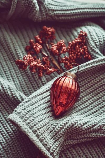 Rode kerstversiering op blauwe geweven trui, minimalistisch kleurenschema, veel textuur. — Stockfoto