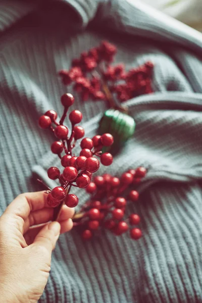 Nők kéz gazdaság piros karácsonyfa dekoráció, minimalista színséma, sok textúra. — Stock Fotó