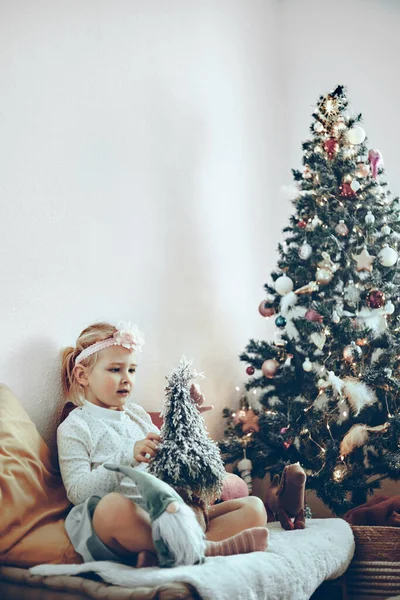 Klein meisje - peuter - spelen met speelgoed en decoraties zitten naast een kerstboom — Stockfoto