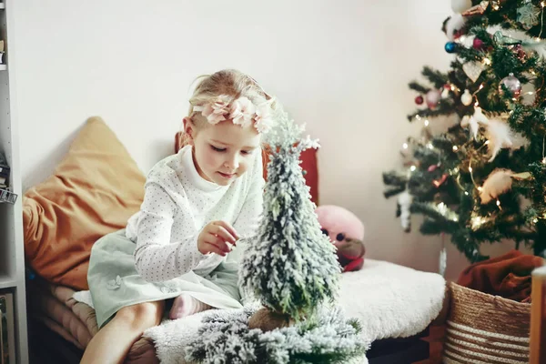 Liten flicka - småbarn - leka med leksaker och dekorationer sitter bredvid en julgran — Stockfoto