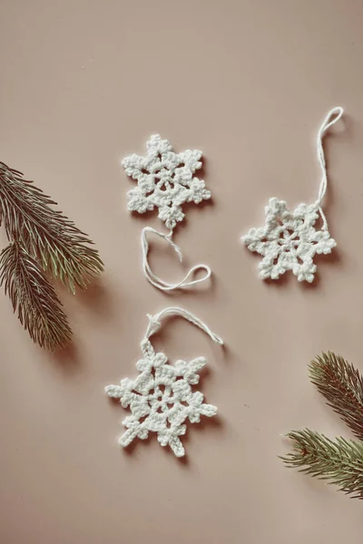 Nachhaltige und umweltfreundliche Weihnachtsdeko, handgehäkelte Baumwollschneeflocken, Flatlay auf beige lizenzfreie Stockfotos