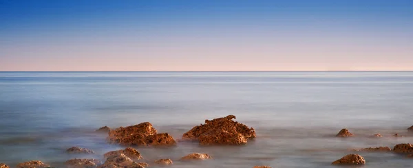 Beautiful sunset over Summer ocean with rocks and vibrant colors — Stock Photo, Image