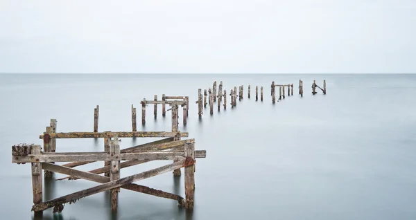 Longa exposição cais abandonado em mar calmo — Fotografia de Stock