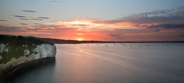 Красивый закат над спокойным морем и скалами
