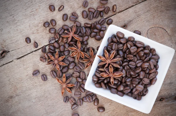 Coffee beans and star anise in a white bowl on wooden background — Stock Photo, Image