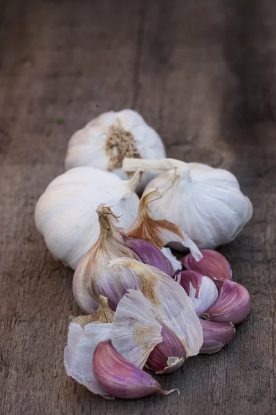 Garlic bulbs on vintage wooden board — Stock Photo, Image