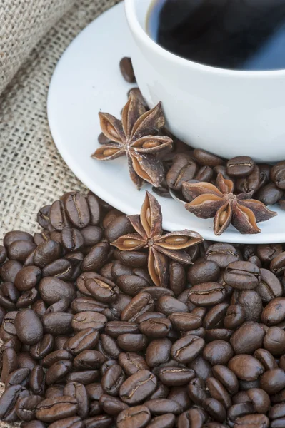 Close up of coffe cup and saucer surrounded by beans on hessian — Stock Photo, Image